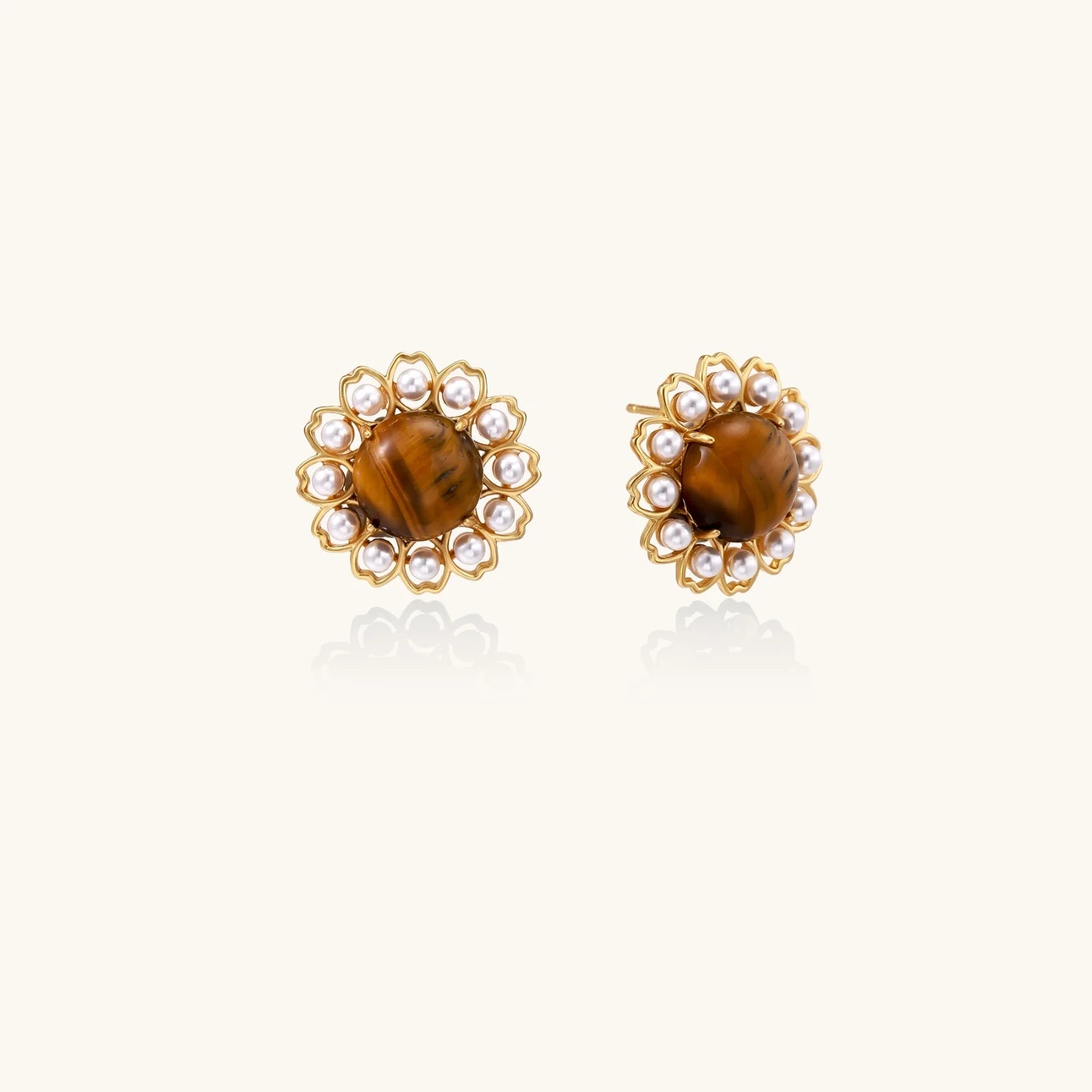 Gold-plated stud earrings with cushion-cut tiger's eye stones surrounded by pearl halos on white background.